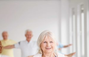 Active Aging Smiling elder lady with towel stretching at the gym