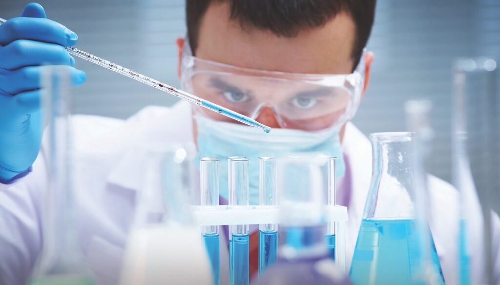 Investigator checking test tubes. Man wears protective goggles