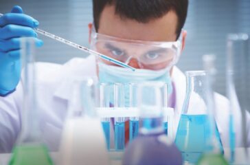 Investigator checking test tubes. Man wears protective goggles