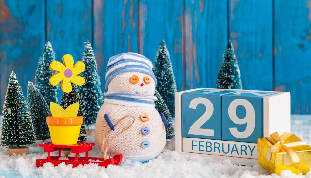 February 29th. Cube calendar for february 29 on wooden surface with snowman, sled, snow, fir and spring flower. Leap year, intercalary day