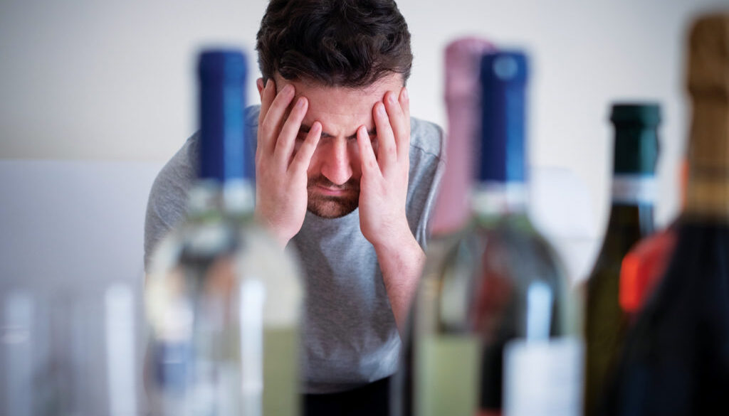 Alcohol addicted man portrait alone with spirit bottle