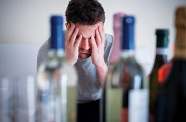 Alcohol addicted man portrait alone with spirit bottle