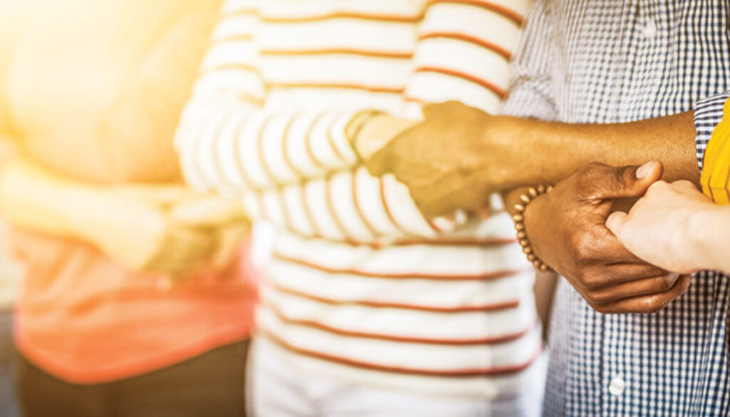 Creative team meeting hands together in line. Young people in casual clothes are holding hands. Unity and teamwork concept.
