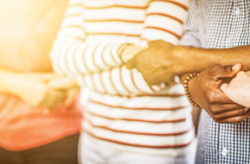 Creative team meeting hands together in line. Young people in casual clothes are holding hands. Unity and teamwork concept.