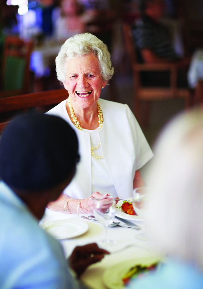 March Event to Teach Seniors How to ‘Staying Safe While Aging in Place’ A cheerful old lady sitting with her elderly friends at lunch at their nursing home