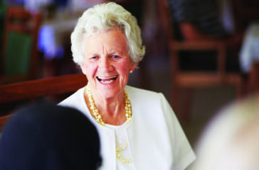 A cheerful old lady sitting with her elderly friends at lunch at their nursing home