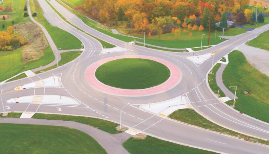 Aerial view of roundabout intersection at first light, with Autumn trees.