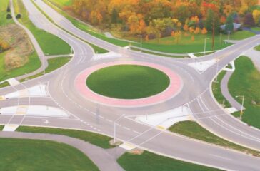 Aerial view of roundabout intersection at first light, with Autumn trees.