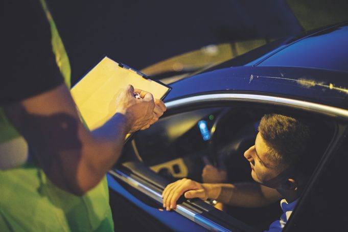 Traffic Enforcement Myths One young person pulled over, looking at the police officer, getting a ticket