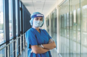 portrait of a young nurse in a blue uniform and a protective shield to protect against a new dangerous virus covid19