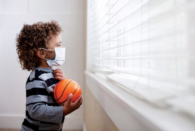 The ‘Other’ Pandemic A young boy looking out the window wearing a protective facemark while seeking protection from COVID-19, or the novel coronavirus, by sheltering in place in his home.
