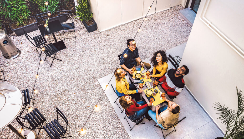High angle top view of happy friends drinking cocktails and having fun at restaurant garden party - Food and beverage concept with young people together at home patio - Dark warm filter