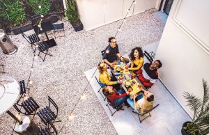 Post-Pandemic Most-Wanted High angle top view of happy friends drinking cocktails and having fun at restaurant garden party - Food and beverage concept with young people together at home patio - Dark warm filter