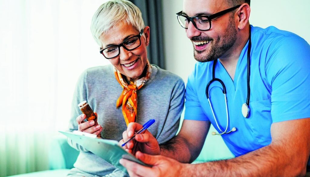 Young smiling doctor is consulting a modern senior woman - patient, on the visit at home