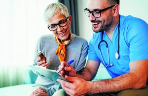 Don’t Recover From Surgery Alone Young smiling doctor is consulting a modern senior woman - patient, on the visit at home