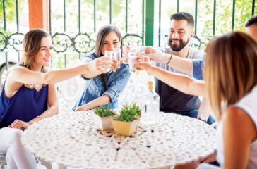 Five good looking Latin friends having fun in a Mexican party drinking tequila shots outdoors