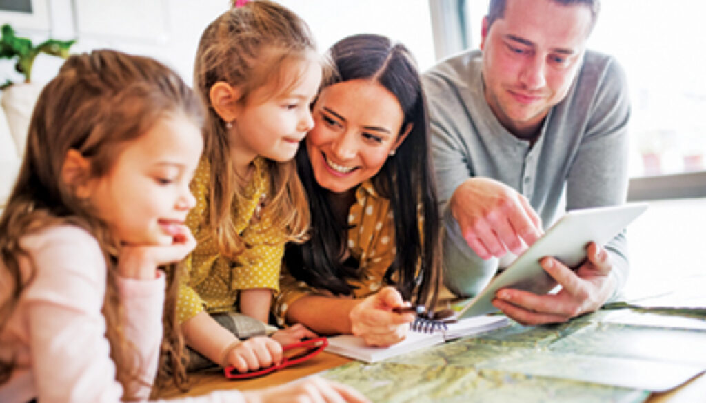 Young happy family with two children and tablet preparing for holidays at home.