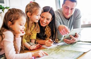 ‘They Don’t Know Something Like This Exists’ Young happy family with two children and tablet preparing for holidays at home.