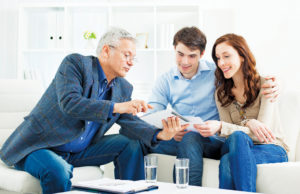 An Agent Can Make All The Difference Young Couple Meeting With Senior Financial Advisor presenting new bank offers and investments on digital tablet PC. Senior Financial Advisor pointing with hand to some new offers.