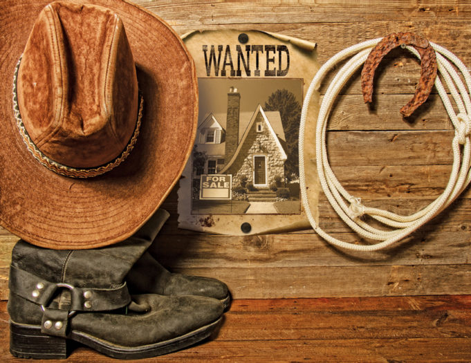 The Wild West Of Real Estate Very rusty old horseshoe symbol of luck and lasso hanging on a wooden wall cowboy hat and boots and blank sheet of paper with place for text