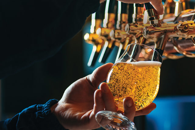 Close up of bartender pouring draft beer in glass