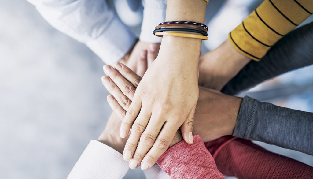 Close up top view of young business people putting their hands together. Stack of hands. Unity and teamwork concept.