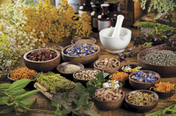 Herbs, berries and flowers with mortar, on wooden table backgrou