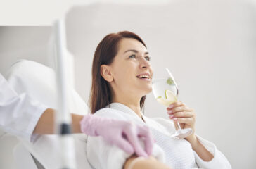 Joyous female patient drinking a healthy beverage during a medical procedure in a beauty clinic