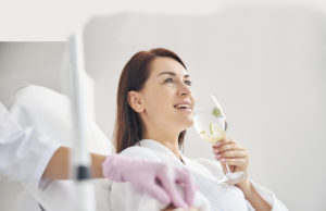 Fast-track to Wellness Joyous female patient drinking a healthy beverage during a medical procedure in a beauty clinic