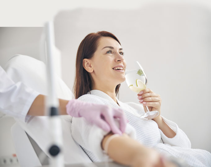 Fast-track to Wellness Joyous female patient drinking a healthy beverage during a medical procedure in a beauty clinic
