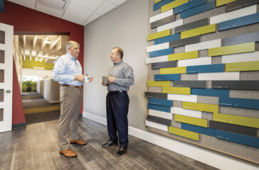 CEO Jim Croft, RA, NCARB (right); and President Mark Jackson, PE, AIA, next to the firm’s wall which displays employees’ professional accomplishments.