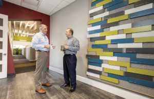 CROFT & Associates CEO Jim Croft, RA, NCARB (right); and President Mark Jackson, PE, AIA, next to the firm’s wall which displays employees’ professional accomplishments.