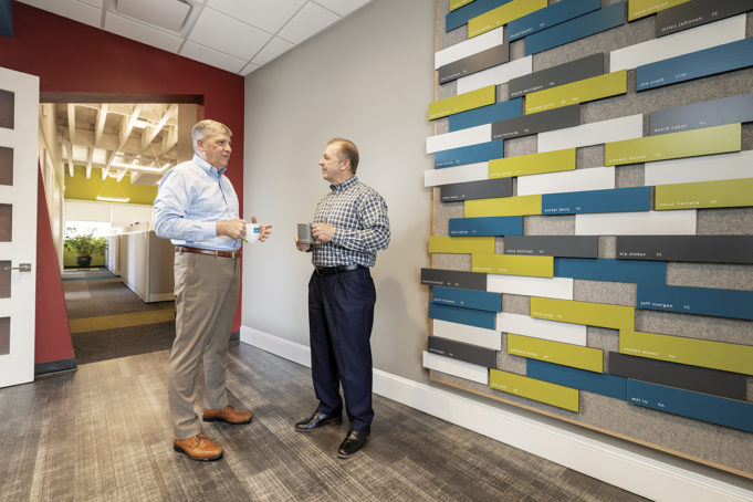 CROFT & Associates CEO Jim Croft, RA, NCARB (right); and President Mark Jackson, PE, AIA, next to the firm’s wall which displays employees’ professional accomplishments.