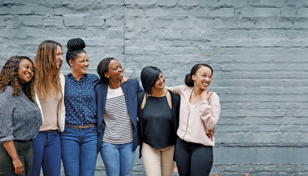 Shot of a diverse group of young women standing together against a gray wall outside