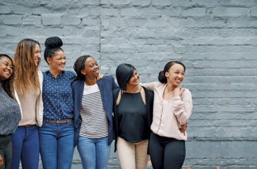 Shot of a diverse group of young women standing together against a gray wall outside
