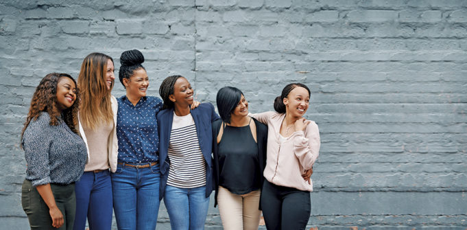A Story Of Hope, Community & Resilience Shot of a diverse group of young women standing together against a gray wall outside