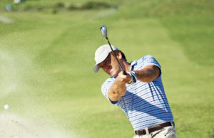 Golf Is A Win-Win! Professional golf player chipping the ball from the sand bunker