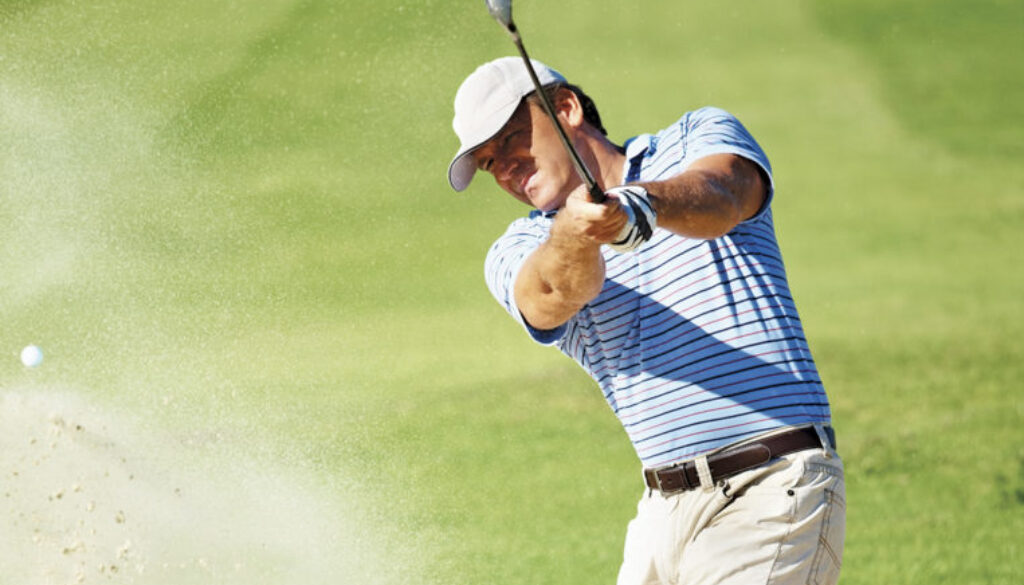 Professional golf player chipping the ball from the sand bunker
