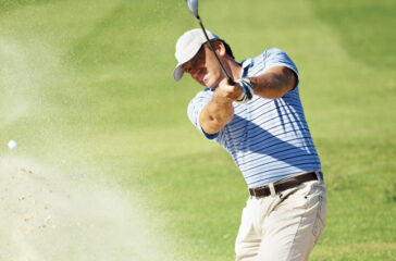 Professional golf player chipping the ball from the sand bunker