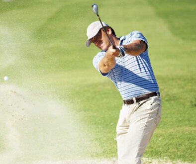 Professional golf player chipping the ball from the sand bunker
