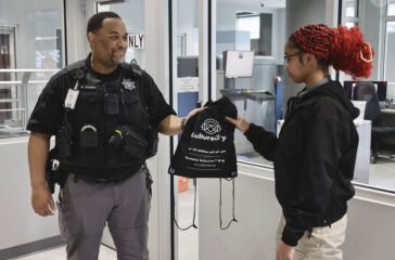 Student receives a KultureCity sensory bag from deputy.
