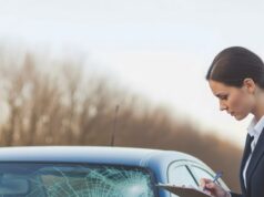 What Can You Do To Combat The High Cost Of Auto Insurance? A professional insurance agent evaluates a car's damaged windshield. The agent notes details on a clipboard, likely preparing an accident report. This scene depicts the process of filing an insurance claim for vehicle damage.