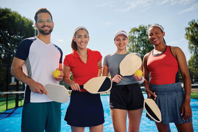 Group,Of,Happy,Athletic,Friends,Playing,Mixed,Doubles,In,Pickleball Group of happy athletic friends playing mixed doubles in pickleball and looking at camera.